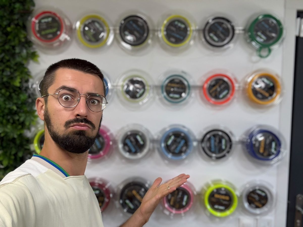 Geoffrey devant le mur de cordages Yonex de la boutique